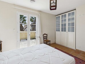 Un dormitorio con cama, una silla, un ventanal corredero y un armario.