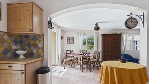 Un coin repas comprenant une table ronde, des chaises, une horloge et un buffet.