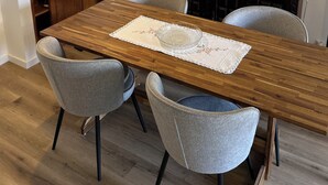 A dining area with a wooden table, grey chairs, a woven light fixture, and decorative wall art. - Casa da Praceta (Porto)