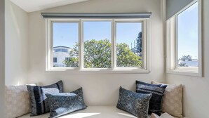 A cozy reading nook with a built-in bench, a window with blinds, and a view of the outside.