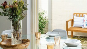 A dining table set with clear glassware, a wooden tray, and a vase with greenery.