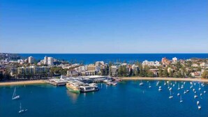 A coastal cityscape with a marina filled with boats, a large cruise ship docked, and a mix of residential and commercial buildings.