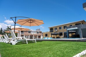A pool area with lounge chairs and umbrellas, a building with a sign reading 'ADONAL,' and a clear blue sky. - Spacious 1-3bedroom apartment with AC, WiFi in amazing Greater Accra Region. (Greater Accra Region)