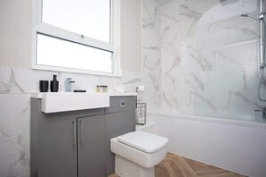 A modern bathroom with a marble shower, a white toilet, and a grey cabinet with a mirror above. - Lydia Terrace | Parking | Wi-Fi (County Durham)