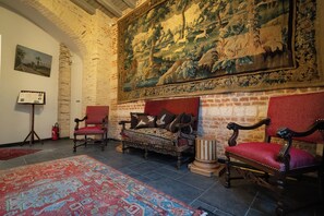 A room with a large tapestry, two red upholstered chairs, a wooden bed, and a patterned rug. - CLOS DU BAILLI (Saint-Omer)