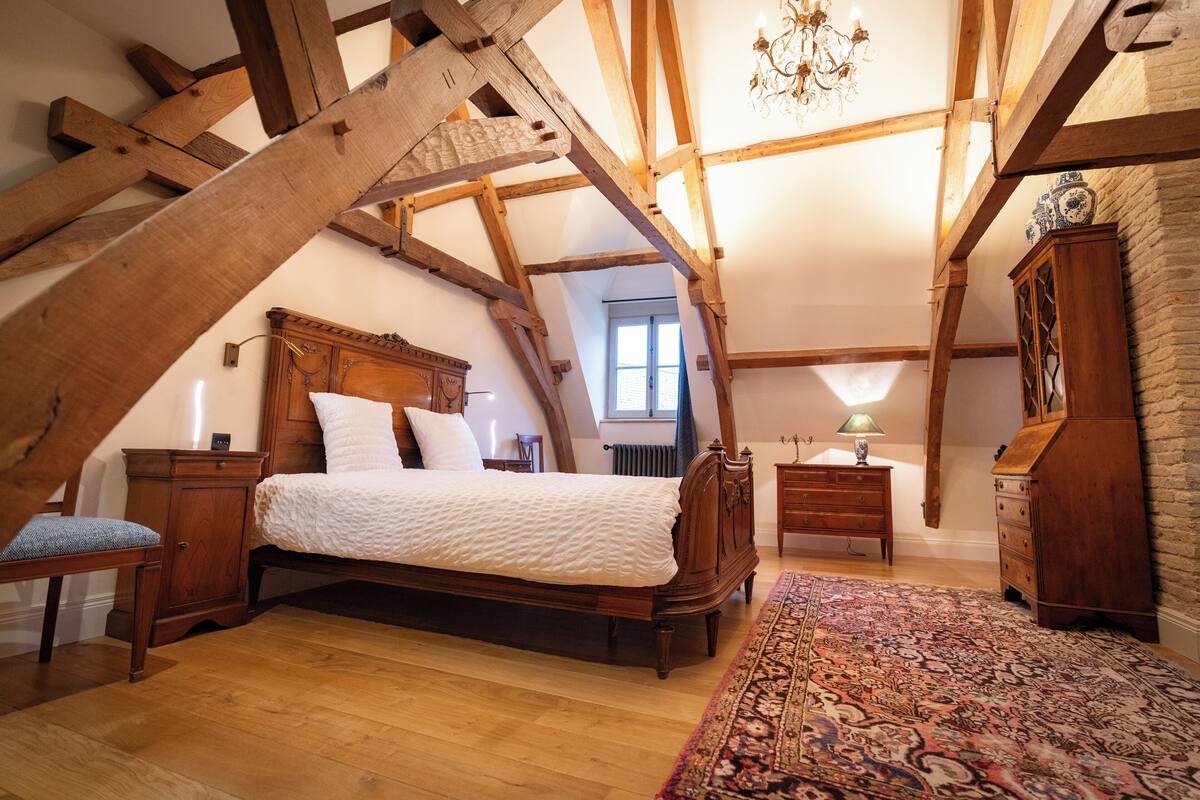 A bedroom with a wooden bed, a nightstand, a dresser, and a patterned rug.