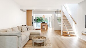 A modern living room with a sofa, coffee table, and staircase.