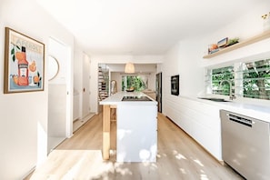 A modern kitchen with a central island, white cabinetry, and a built-in dishwasher. - Serenity on Sunshine Easy Walk to Village Beach (Sunshine Beach)