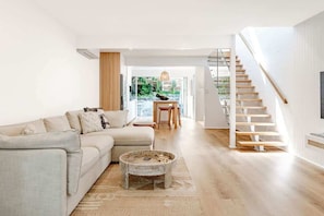 A modern living room with a sofa, coffee table, and staircase.