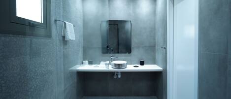 A modern bathroom with a large mirror, a round sink, and a toilet.