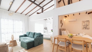 A modern living room with a teal sofa, wooden dining table, and chairs. - Loft Centrale by Deserve (Paphos)