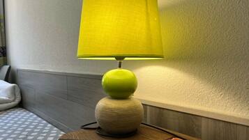 Una lámpara con pantalla amarilla sobre una mesa de madera en una habitación de hotel.