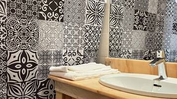 Un baño con papel tapiz estampado, un lavamanos y un espejo.