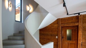 Ein modernes Interieur mit einer geschwungenen Treppe, Holzvertäfelung und einer Tür mit Glasfenster.