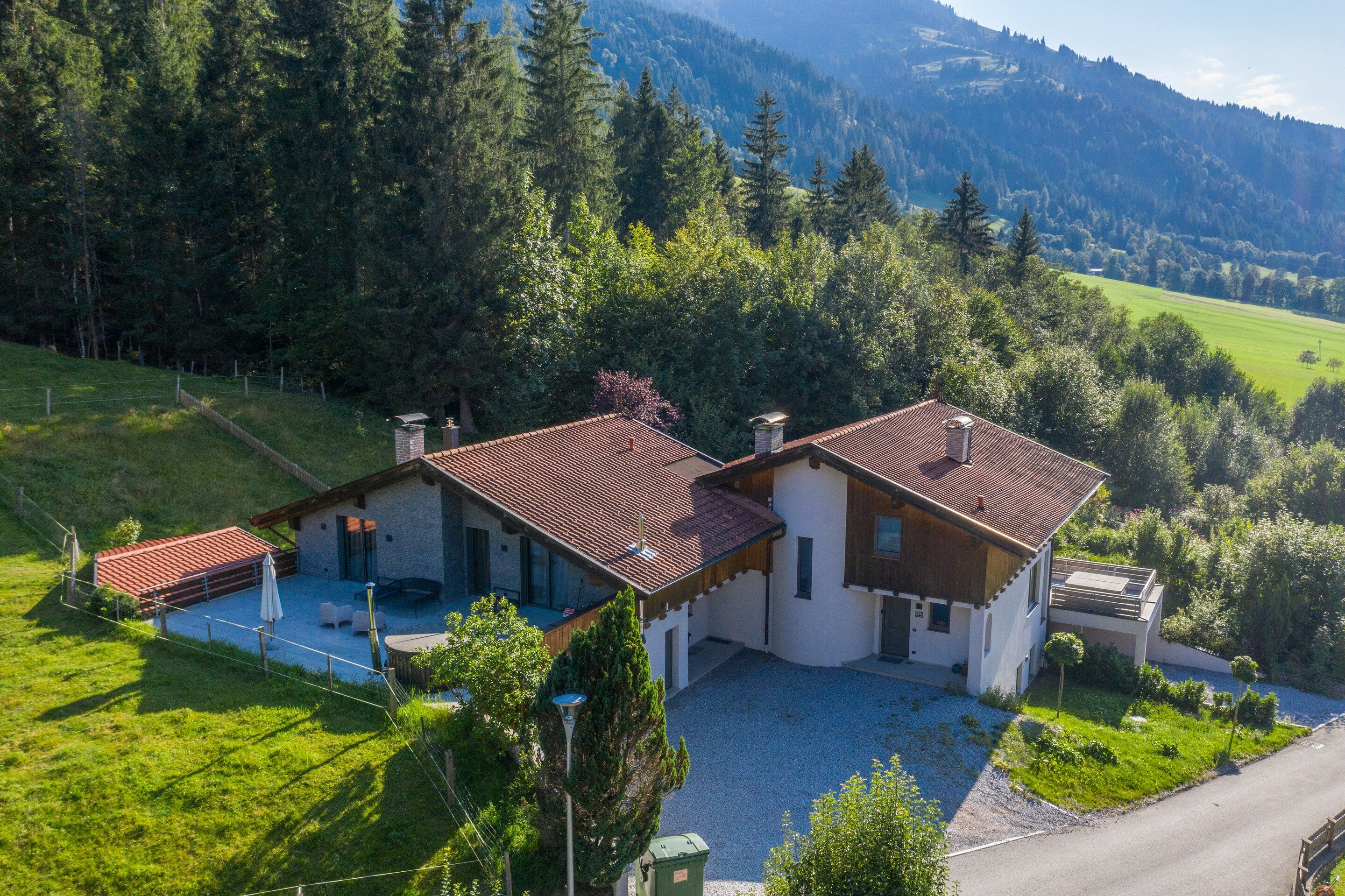 Une maison à deux étages, avec un toit recouvert de tuiles rouges, une allée pavée et un jardin verdoyant.