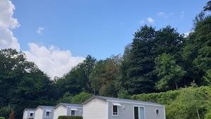 A row of mobile homes with picnic tables in a grassy area, surrounded by dense forest. - Chalet in Olloy-sur-viroin With Patio (Viroinval)