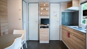 A compact kitchen with wooden cabinets, a built-in stove, and a window overlooking greenery. - Chalet in Olloy-sur-viroin With Patio (Viroinval)