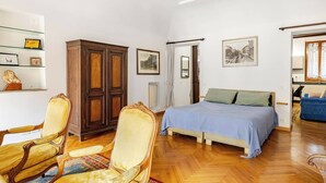 A bedroom with a bed, a wooden wardrobe, a chair, and a blue sofa. - ***Newly Restored*** Spanish Steps Cosy apartment (Roma)