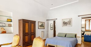 Une chambre à coucher comprenant un lit, une armoire, une chaise, une étagère avec des objets et une porte.