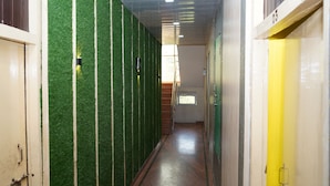 A hallway with artificial grass walls, a wooden floor, and a window at the end.