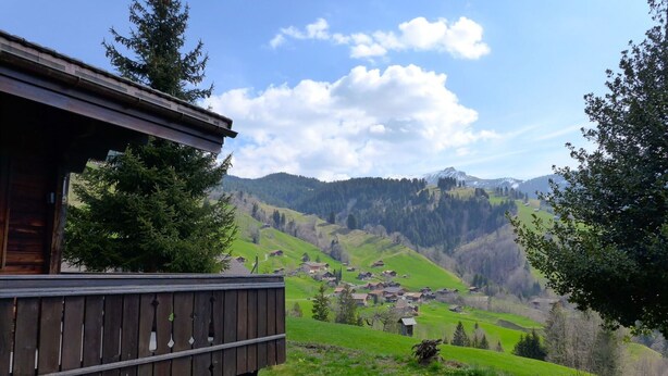 A wooden cabin with a balcony overlooking a valley with houses and mountains. - Stunning  villa for 3 people with TV, patio, pets allowed and panoramic view (Habkern)
