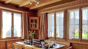 A wooden dining room with a table set for two, a cabinet, and a view of the outdoors. - Stunning  villa for 3 people with TV, patio, pets allowed and panoramic view (Habkern)
