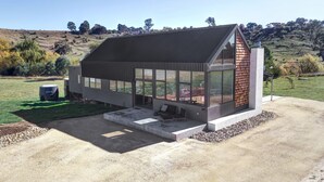 Une maison moderne dotée de grandes fenêtres, d’un toit en pente et d’un espace patio.