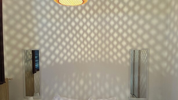 A hotel room with a bed, two bedside tables with lamps, a wall-mounted TV, and a window with curtains. - Town/country house 6 km from Tours, fitted kitchen, garden, pets welcome. (Fondettes)