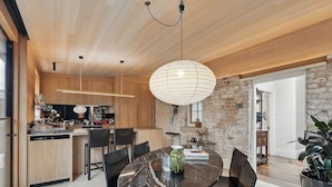 A modern kitchen with wooden cabinets, a marble dining table, and black chairs. - King St Cottage: Central and Stylish (Hobart City)