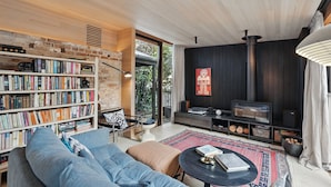 A modern living room with a bookshelf, a sofa, a coffee table, and a fireplace. - King St Cottage: Central and Stylish (Hobart City)