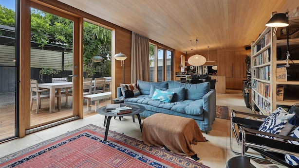 A spacious living area with a blue sofa, a coffee table, and a bookshelf. - King St Cottage: Central and Stylish (Hobart City)