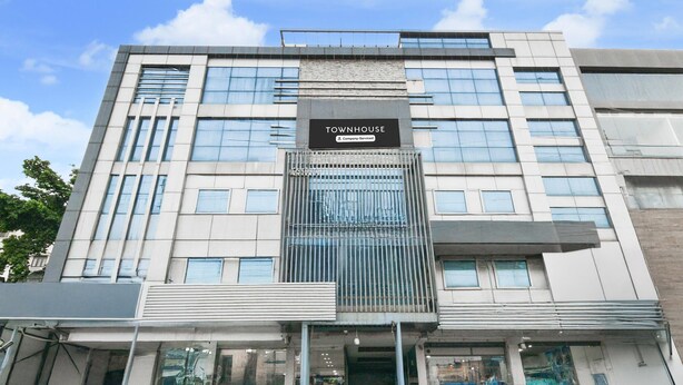 A modern townhouse building with a prominent entrance, large windows, and a sign indicating it is a company-serviced property. - Elegant Stays at Vanasthalipuram Hyderabad (Hyderabad)