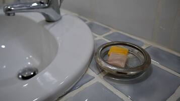 A bathroom sink with a chrome faucet and a metal strainer with a yellow object on it.