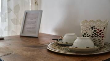 A table with a tray holding two cups and a teapot, a framed menu, and a crocheted basket.