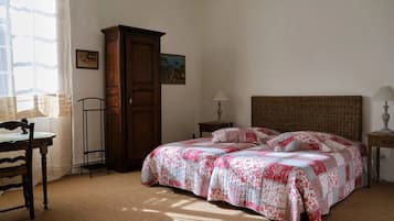 A bedroom with a bed, two bedside tables, a wooden wardrobe, and a desk with a chair.