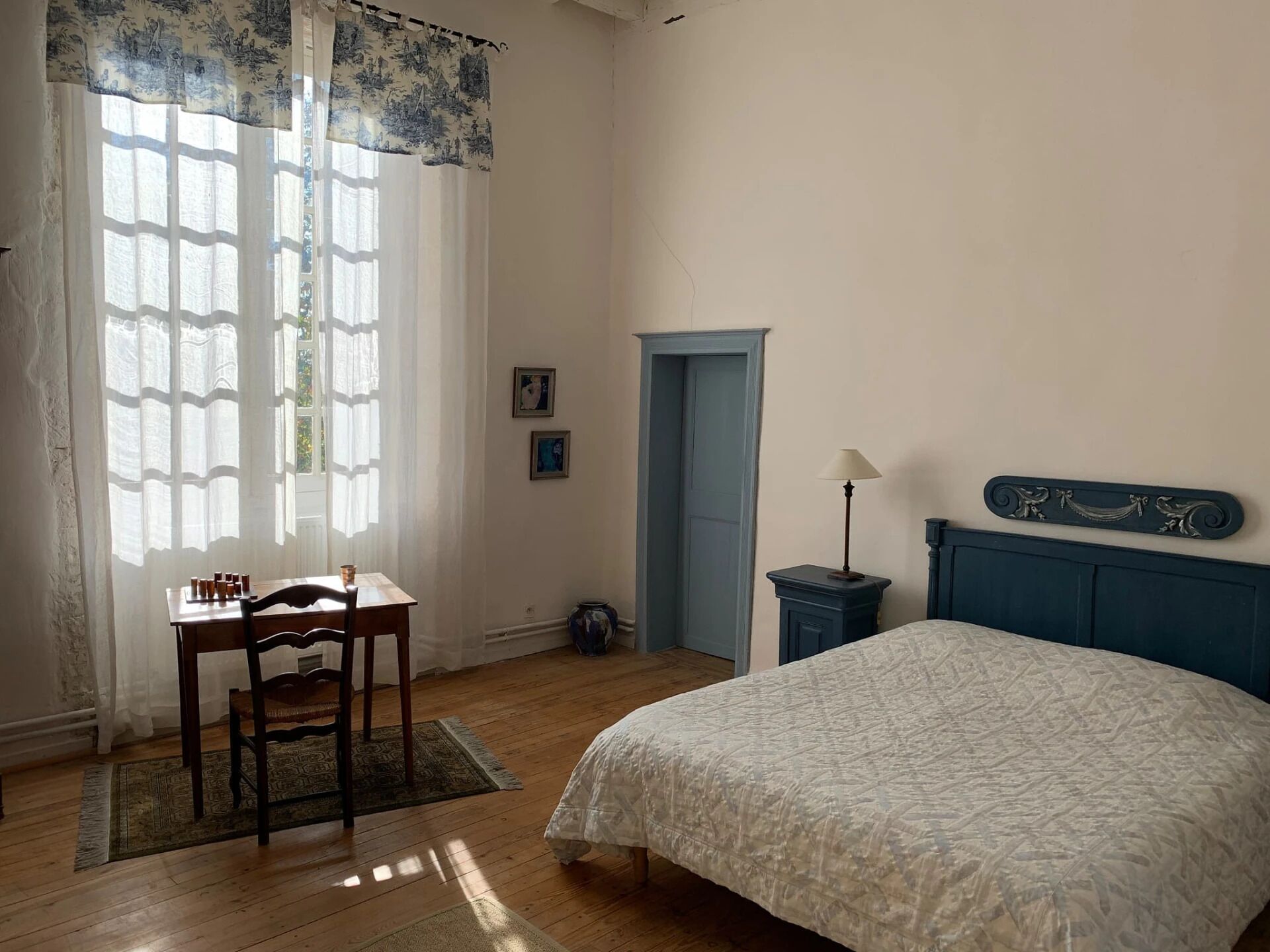 Una camera da letto con un letto, una scrivania con sedie, una lampada e una porta.