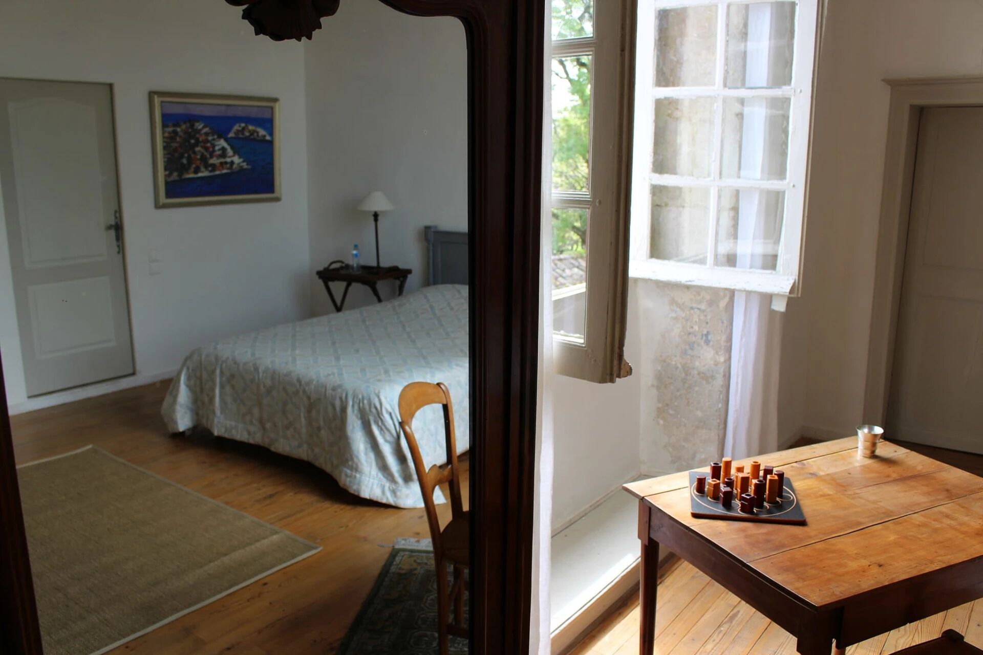 Une chambre à coucher avec un lit, une table de chevet, une lampe et une fenêtre.