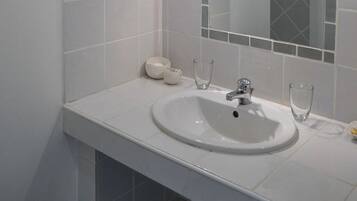 A bathroom with a white sink, a mirror, and a tiled wall.