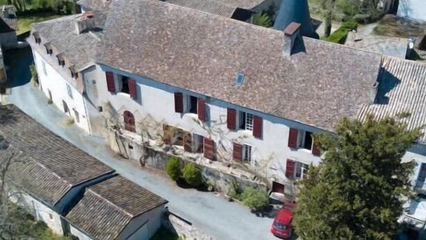 An aerial view of a traditional European-style building with a steeply pitched roof, multiple chimneys, and a prominent tower. - L Ancien Couvent Cahuzac (Cahuzac)