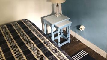 Une pièce comprenant un lit, une petite table avec une lampe et un luminaire fixé au mur.