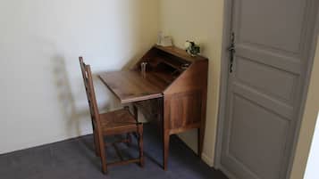 Ein Holztisch mit einem Stuhl in einem Raum mit geschlossener Tür und einem kleinen Regal mit Dekoration.