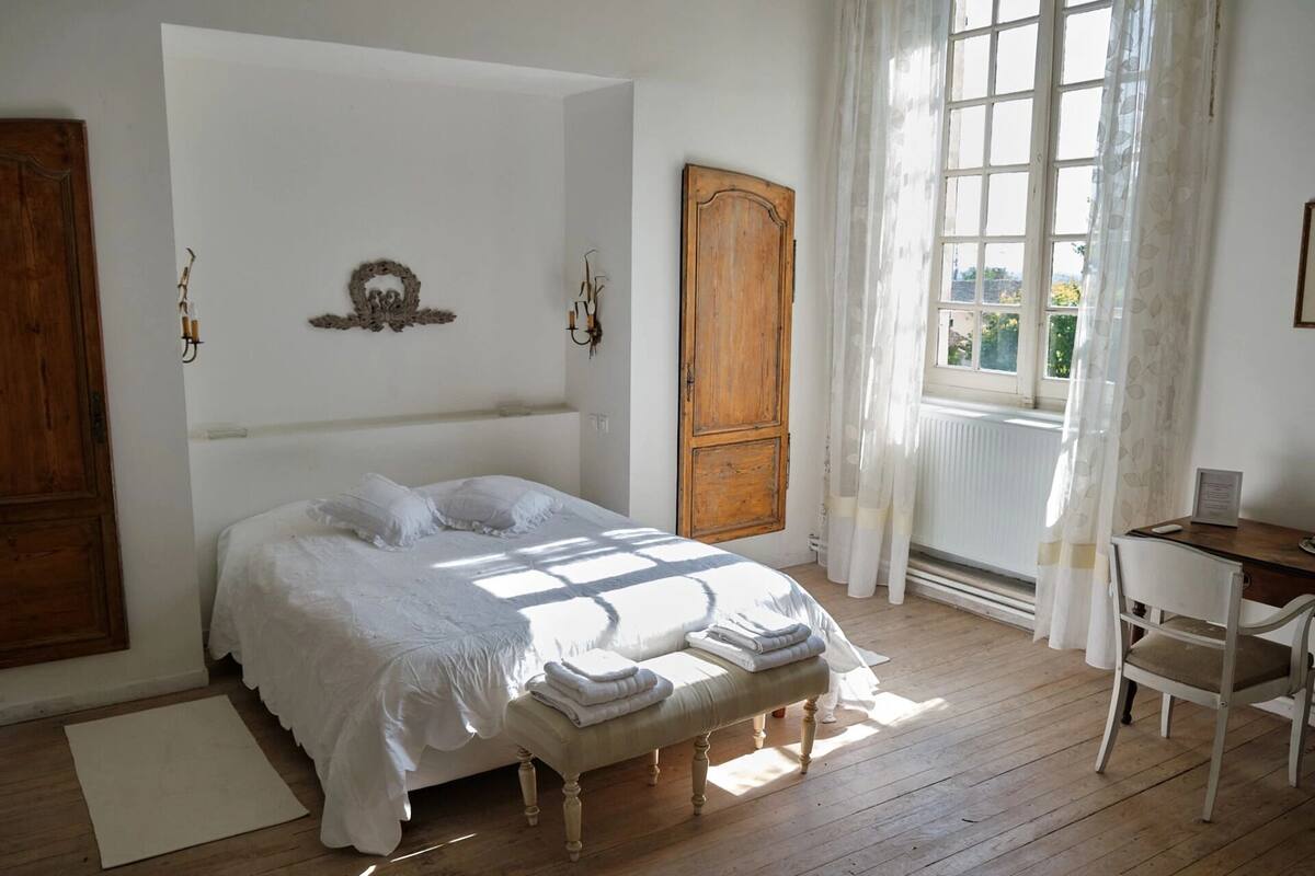 Een slaapkamer met een groot bed, een houten garderobe, een bureau en een stoel.