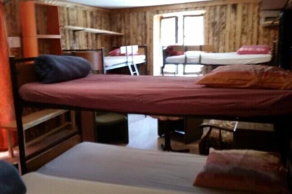 Ein kleines Zimmer mit Etagenbetten, einem Schreibtisch und einem Stuhl.