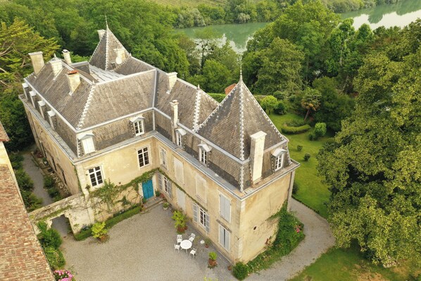 A historic building with a courtyard, surrounded by lush greenery and a lake.