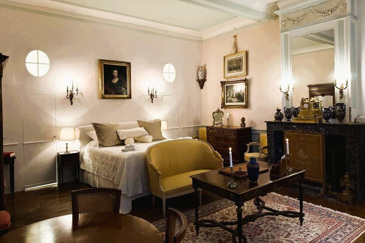 Un dormitorio con cama, una silla, una mesa, un tocador y un espejo.