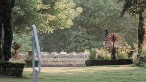A pool area with a seating area and a statue in the background. - Le Château D'Estrac (Hastingues)