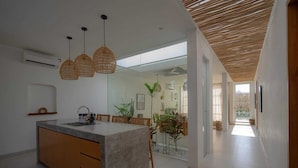 A modern kitchen with a central island, pendant lights, and a view to a dining area. - Modern 3 bedrooms pool villa near the beach, shops, and restaurants (Bali)