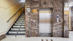 A marble staircase leading to an elevator with a sign indicating a bar on the first floor. - Super Townhouse Koyambedu Royal Plaza (Chennai)