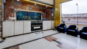 A reception area with a marble wall, a reception desk labeled "TOWNHOUSE," and three black chairs. - Super Townhouse Koyambedu Royal Plaza (Chennai)