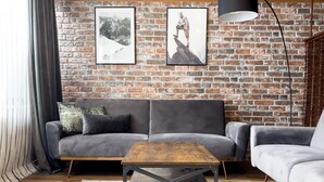 A living room with a brick wall, two sofas, a coffee table, and a patterned rug.